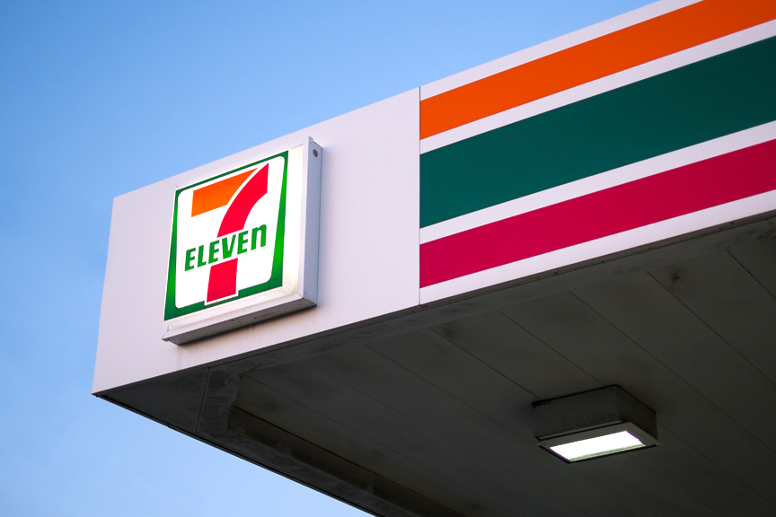 7-Eleven signage and awning exterior against a blue sky.
