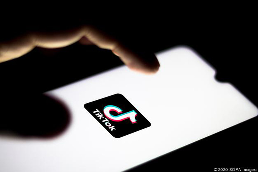 Hand opening tiktok app on smartphone with hand and background in shadow.